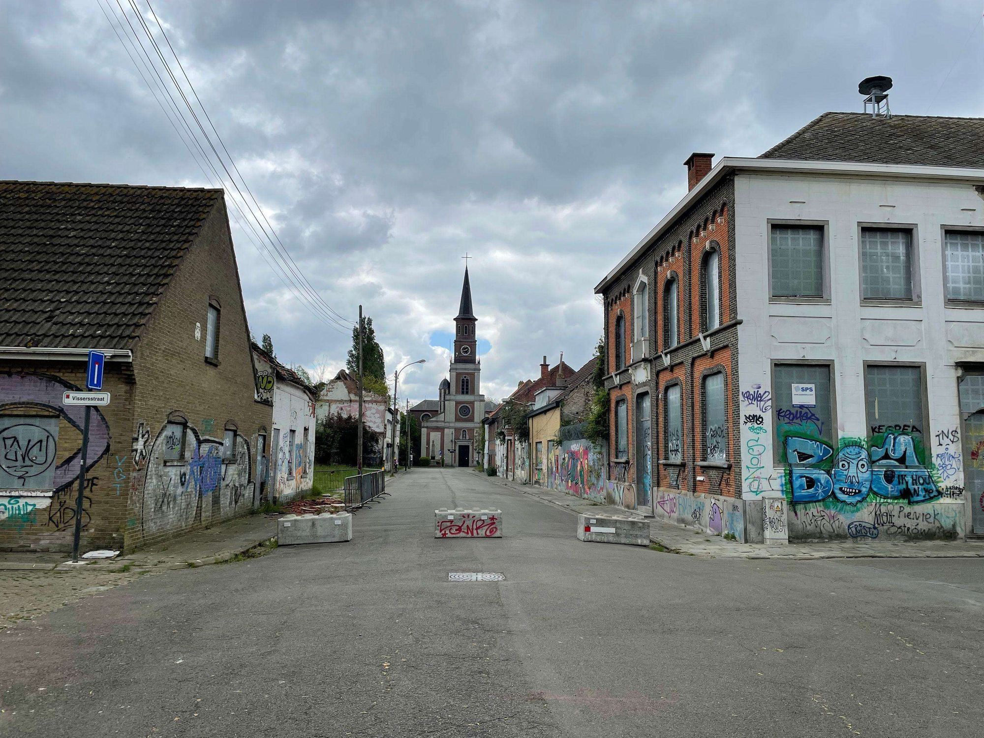 a photograph of the streets in the ghosttown of doel (spookstad doel). the photograph shows houses and the church