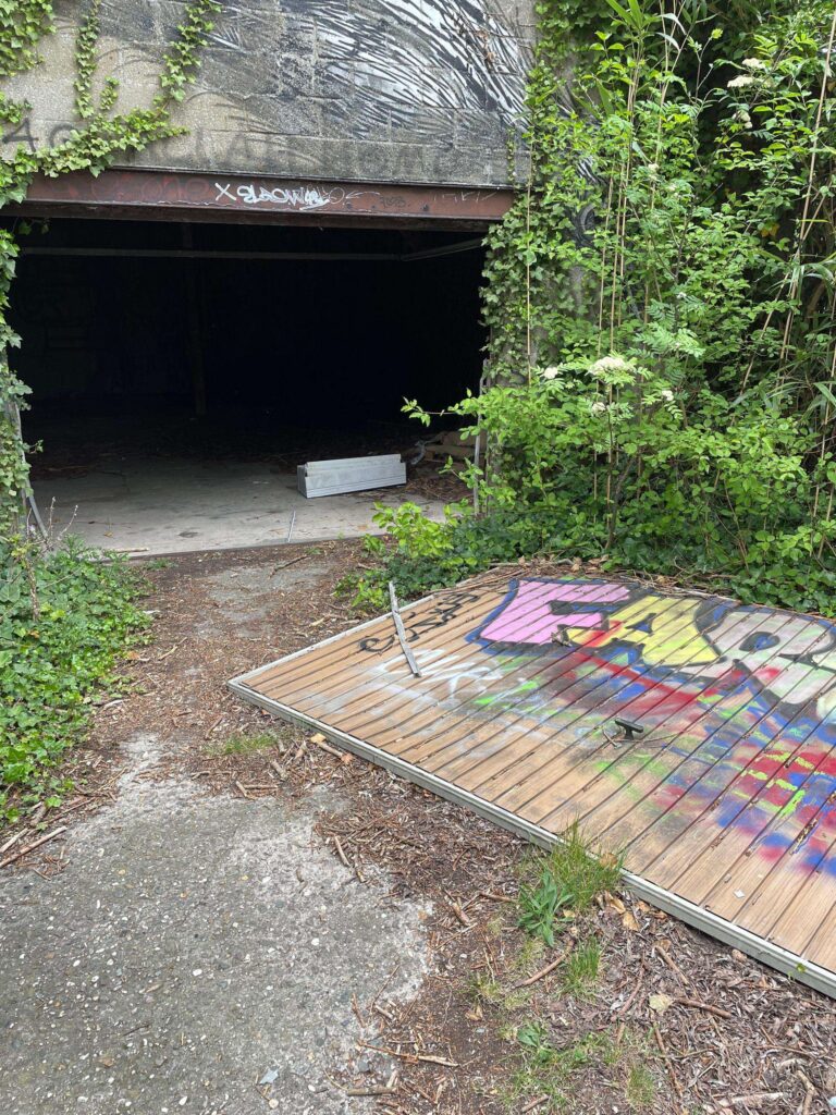 a photograph of an abandoned car garage in belgium, the door has been forced