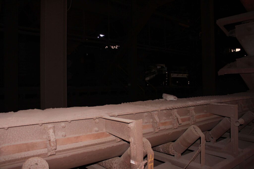a photograph of a conveyor belt inside an abandoned steel factory called hfb. the conveyor belt is rusty