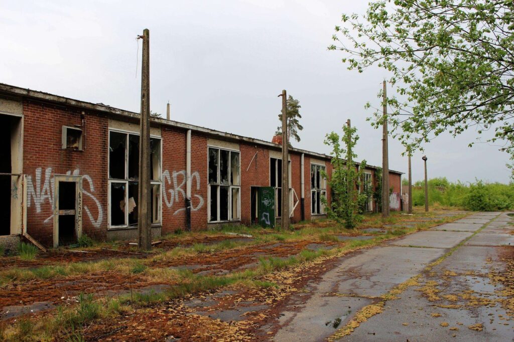 a photograph of a building in a former german munitions depot location in the antwerp region of belgium. the building is heavily vandelized