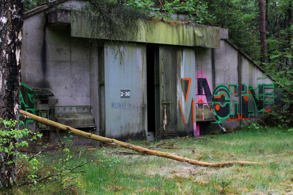 a photograph of an bunker in an abandoned munitions depot in belgium. the bunker door has the numbers 2-30 written on it