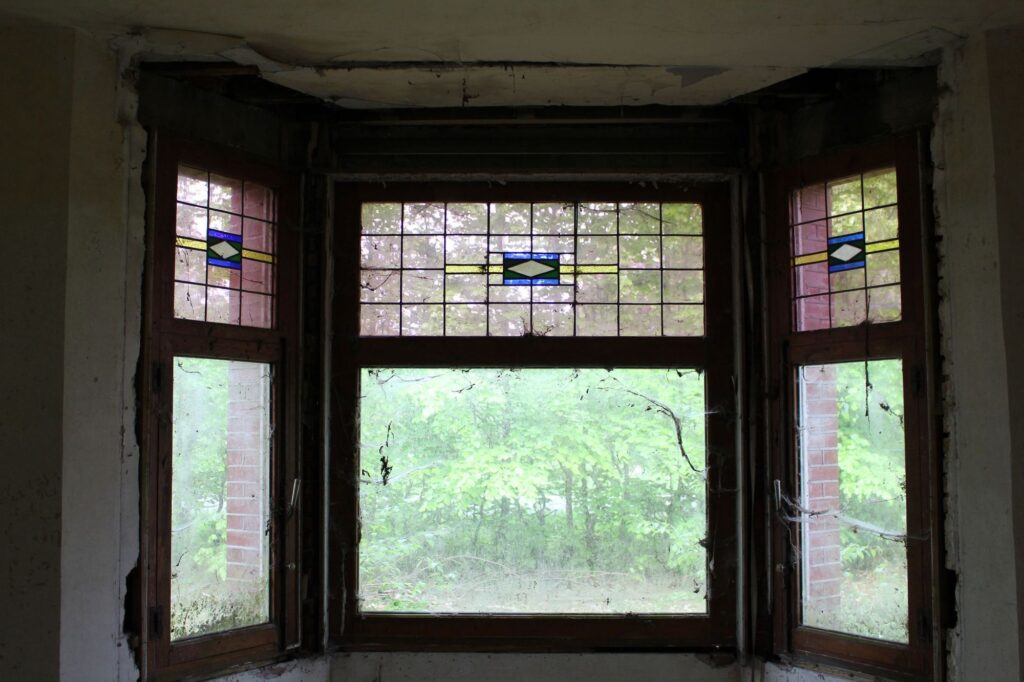 a photograph of windows in an abandoned building. the glass is made of partially stained glass