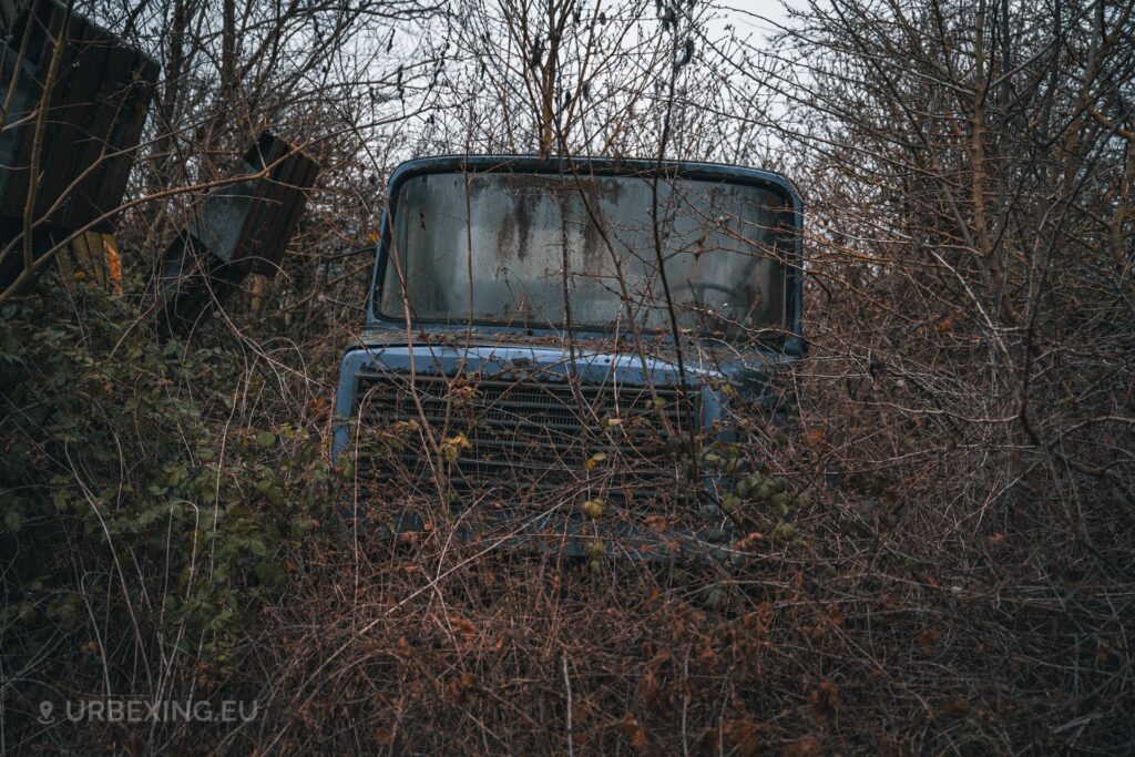 a photo of a blue truck that is abandoned. nature has taken over the truck