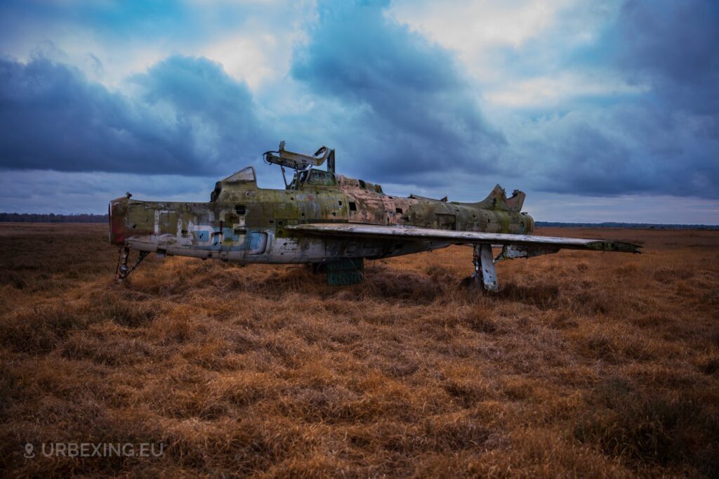 a photograph of an abandoned f84f thunderstreak in a military base in belgium