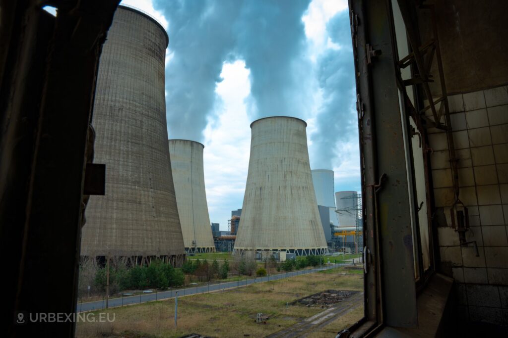 a photo of several cooling towers at an active power plant. the cooling towers are outputting steam from the top.