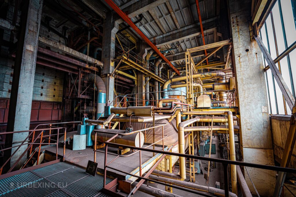 a photo of the inside of a boiler house in a power plant; the photo shows some boilers and tubes. the name of the power station is kraftwerk b