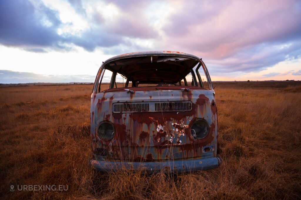 a photograph of a forgotten van located in a military base. the van is rusting and decaying