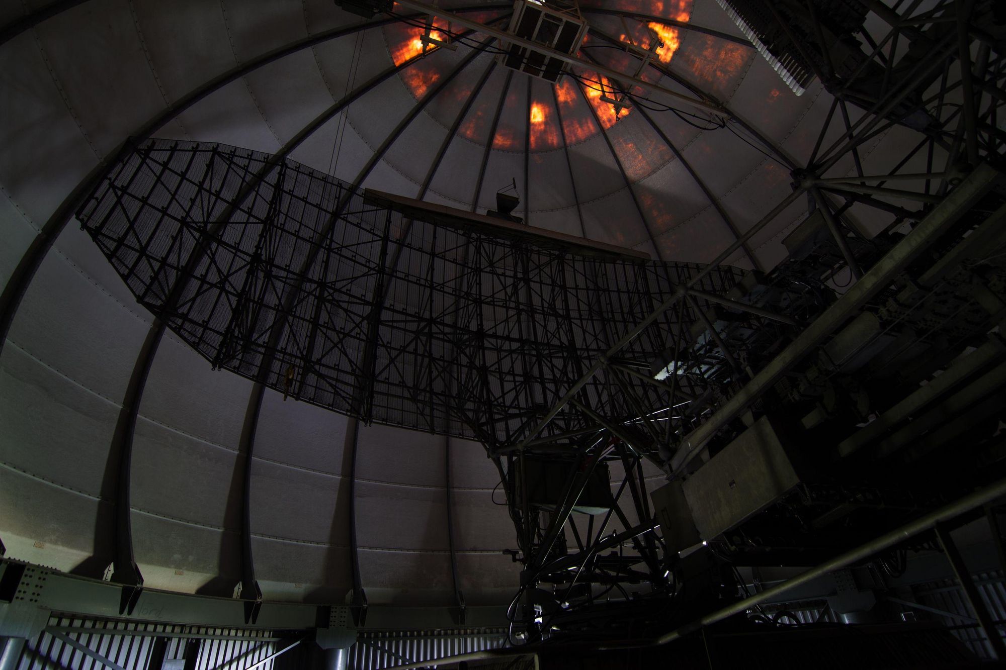 a photograph of a military grade medium power radar in a weather dome. the radar is located in an abandoned nato facility