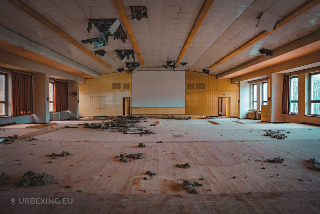 a photo of a small auditorium in an abandoned building, the chairs have been removed