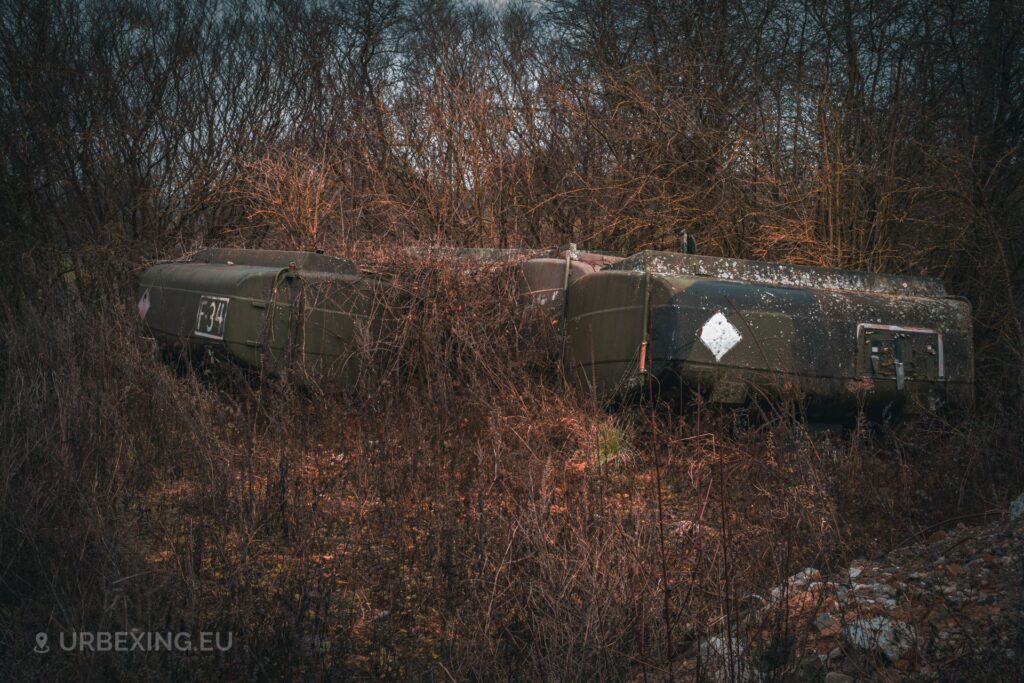 a photo of four tank truck trailers in an abandoned vehicle storage