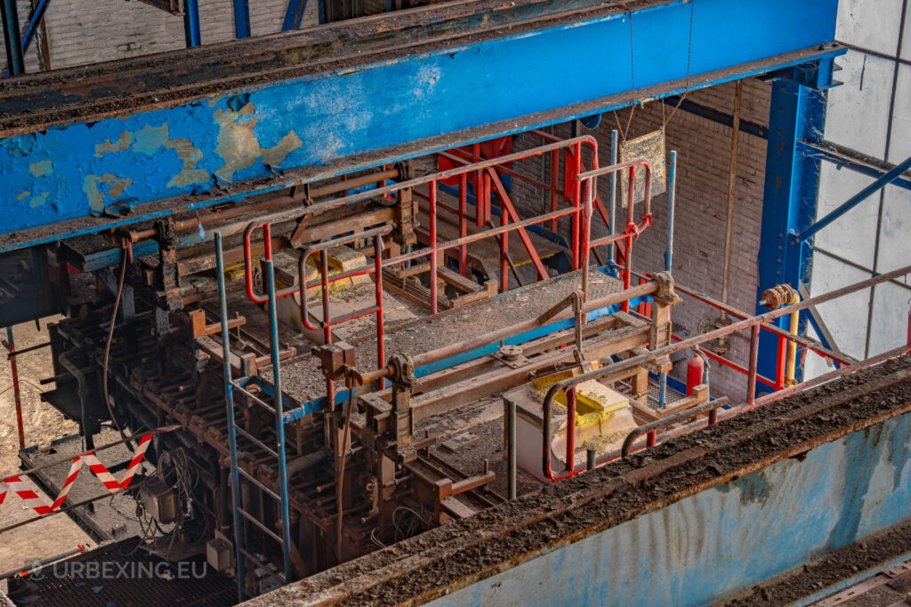 a photograph taken inside an abandoned glass factory called "de glasfabriek schiedam". The photograph shows a bridge over the transporting belt from a glass oven.