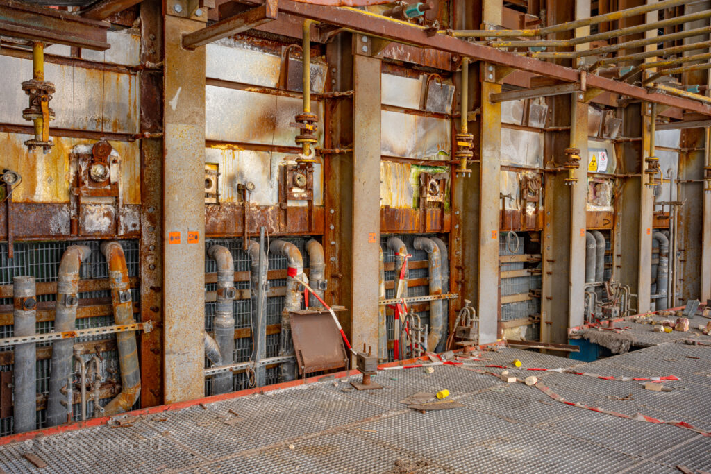 a photograph taken inside an abandoned glass factory called "de glasfabriek schiedam". The photograph shows the back of glass furnaces or ovens.