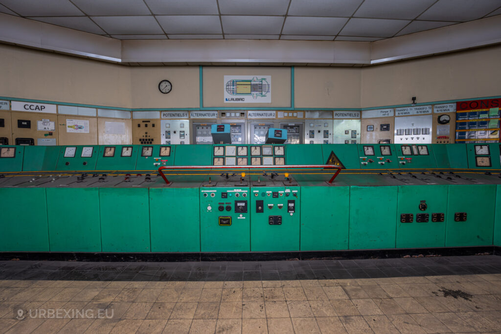 a photograph taken in at an urbex location called blue power plant. the photograph shows a close up view of the center part of the blue control panel in the control room. many buttons and meters can be seen.