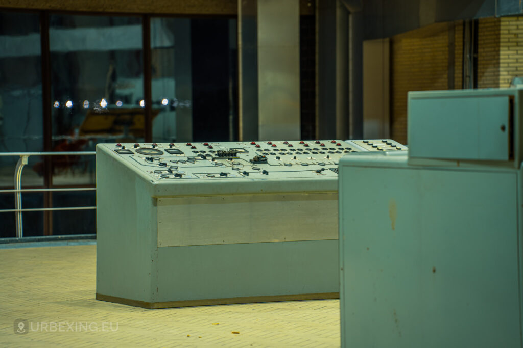 A close-up shot of an old control panel in an abandoned radio transmitting facility, featuring numerous dials, switches, and meters. The panel is part of the Lost Frequencies urban exploration site, showcasing the deteriorated state of the industrial equipment.