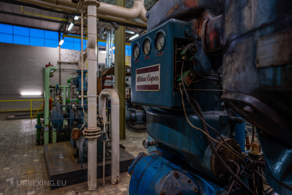 A close-up of an Atlas Copco machine in the abandoned EMGO factory in Lommel, Belgium, part of the water treatment system, showcasing industrial decay amidst the factory's derelict state.