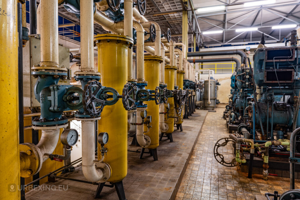 A close-up of industrial valves and pipes inside the abandoned EMGO factory in Lommel, Belgium, highlighting the detailed remnants of the factory's water treatment system amidst its state of decay.