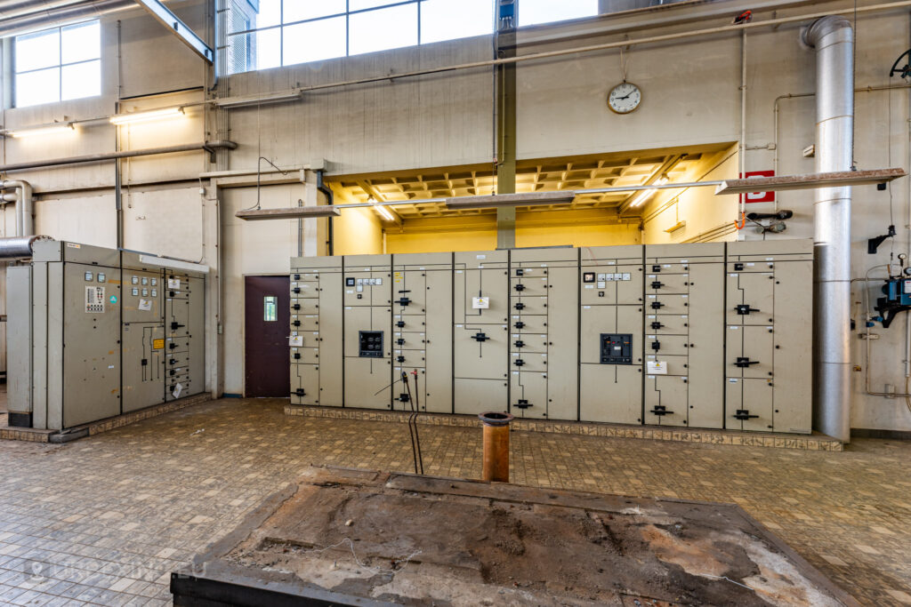 The abandoned EMGO factory in Lommel, Belgium, displaying an array of control panels from its water treatment system, highlighting the industrial decay and forgotten operations of this historic site.