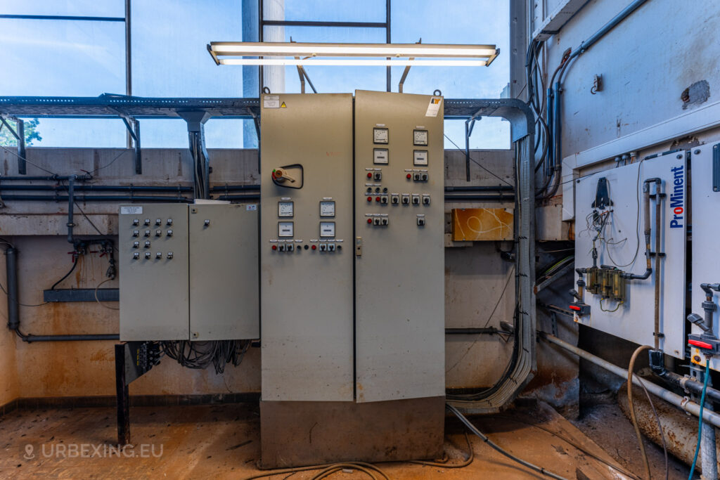 A detailed view of a control panel in the abandoned EMGO factory in Lommel, Belgium, showcasing the factory's extensive electrical system amidst signs of decay and neglect.