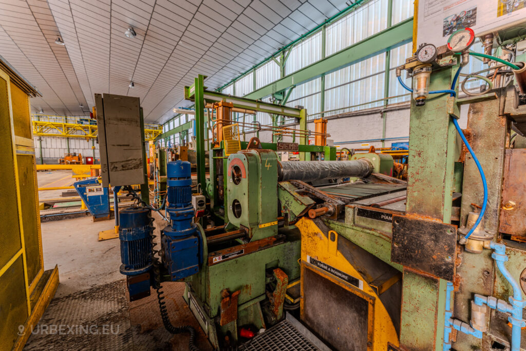 Close-up of green and yellow machinery with blue motor components inside the abandoned ArcelorMittal Marchin plant in Liège, Belgium.