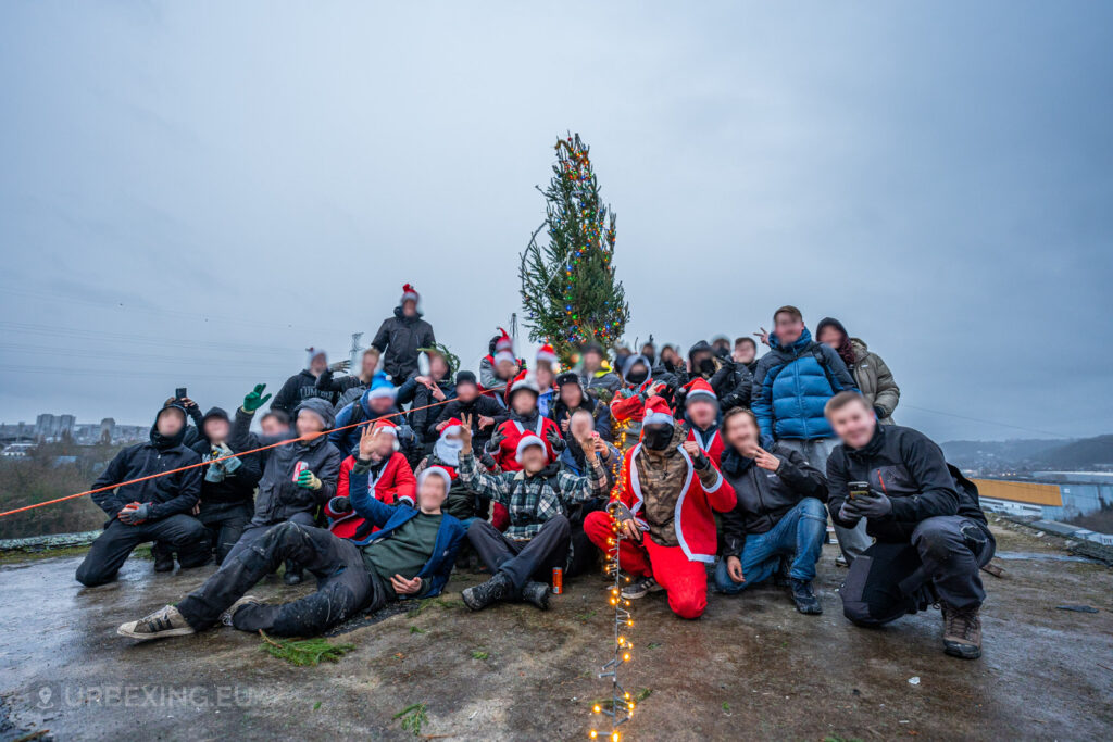 Urban explorers celebrate their festive adventure with a group photo in front of a decorated Christmas tree on the rooftop of the abandoned HF6 power plant in Seraing, Belgium, combining holiday spirit with the thrill of urban exploration.