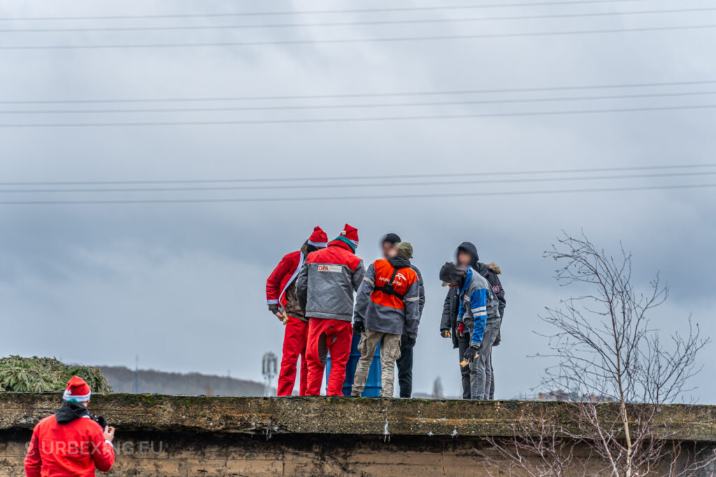 A group of urban explorers gathers on the rooftop of the abandoned HF6 power plant in Seraing, Belgium, blending festive attire with the stark surroundings of this industrial site.