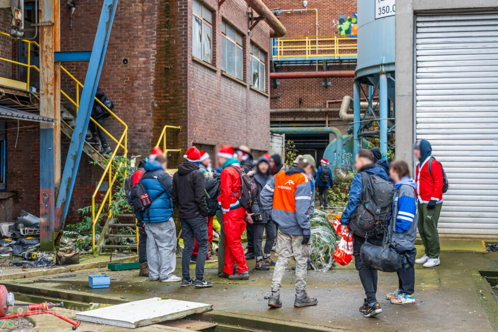 Urban explorers prepare for their festive adventure at the abandoned HF6 power plant in Seraing, Belgium, gathering equipment and a Christmas tree in the industrial courtyard.