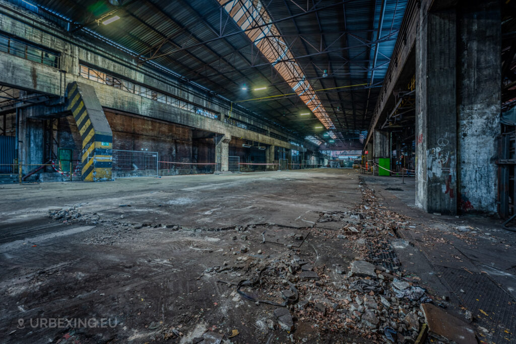 Interior of the abandoned Vallourec steel mill in Düsseldorf-Rath, featuring rusted industrial beams, cracked flooring, and decayed walls, showcasing the remnants of steel tube manufacturing.