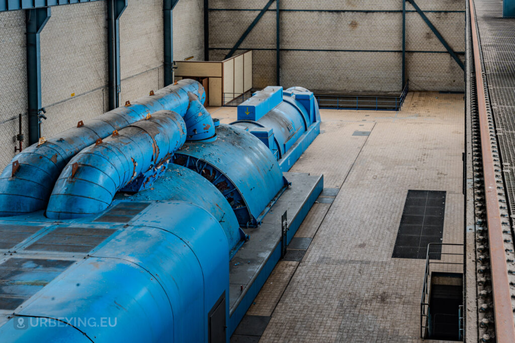 Angled overhead view of blue turbine units with rusted pipes in the abandoned Kraftwerk Voerde, Voerde, Germany.