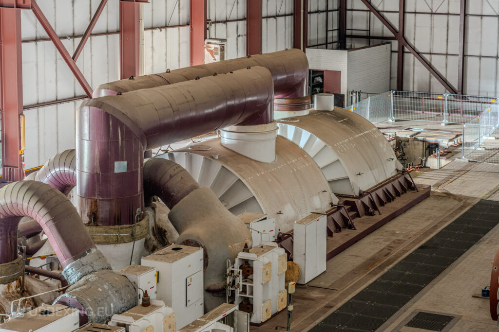 Close-up of large industrial turbines and curved ducts in the abandoned Kraftwerk Voerde power station, Germany.