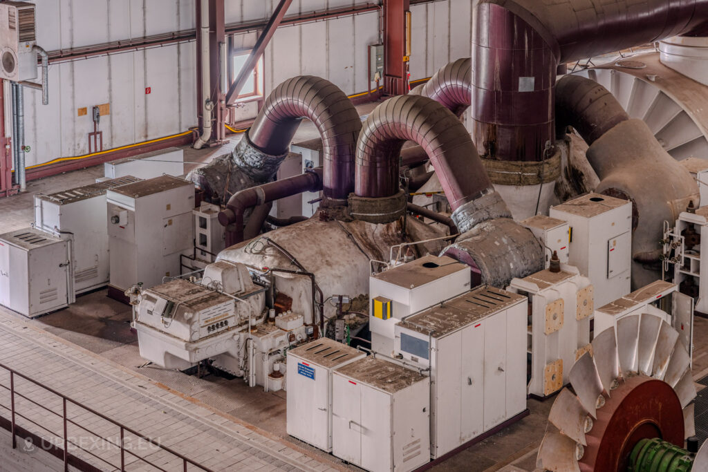 Overhead view of industrial machinery and curved pipes in the turbine hall of the abandoned Kraftwerk Voerde, Germany.