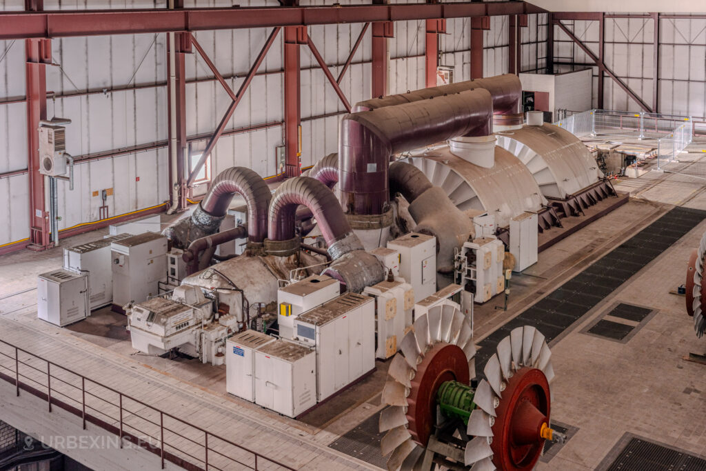 Wide-angle view of turbine machinery and industrial components in the turbine hall of the abandoned Kraftwerk Voerde, Germany.