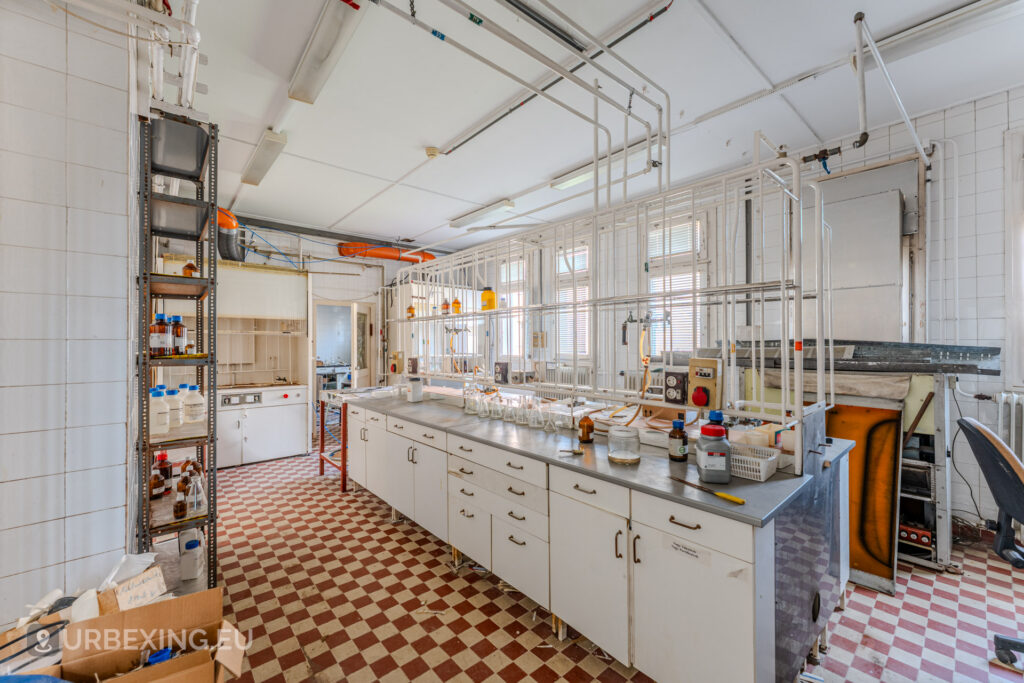 Photograph of an abandoned laboratory, showing workstations, fume hoods and bottles with chemicals