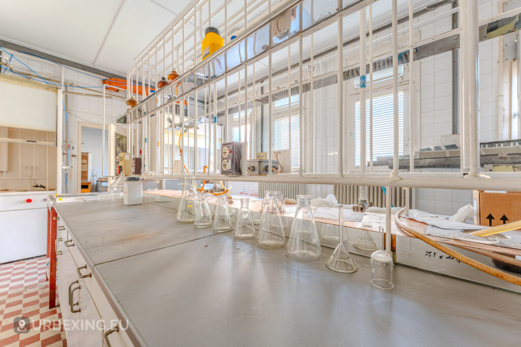 Empty workstation inside of an abandoned laboratorium, on the workstations are empty bottles, flasks and beakers