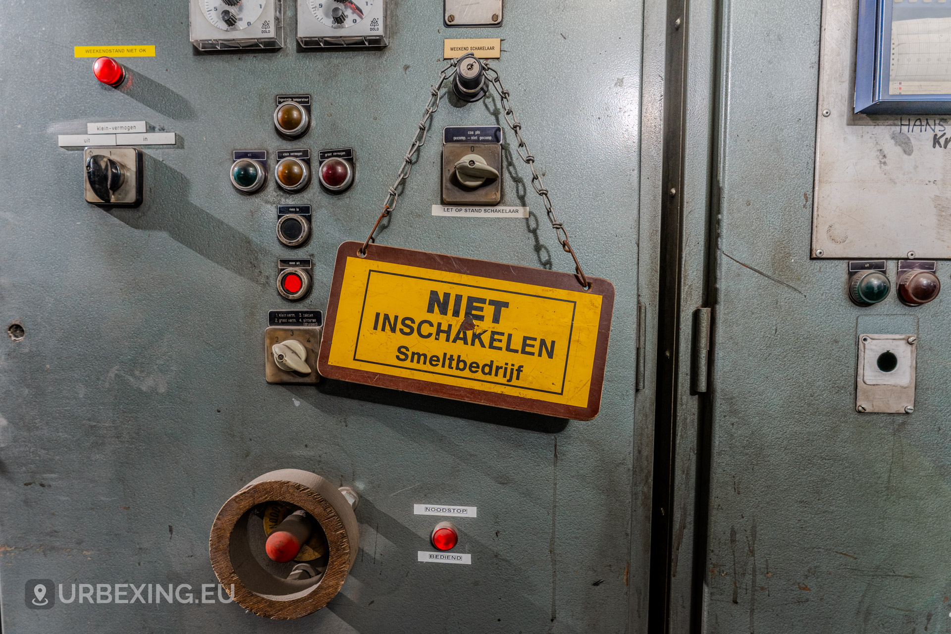 Close up photograph of a yellow sign hanging from a control panel, the sign has black text saying "NIET INSCHAKELEN Smeltbedrijf"